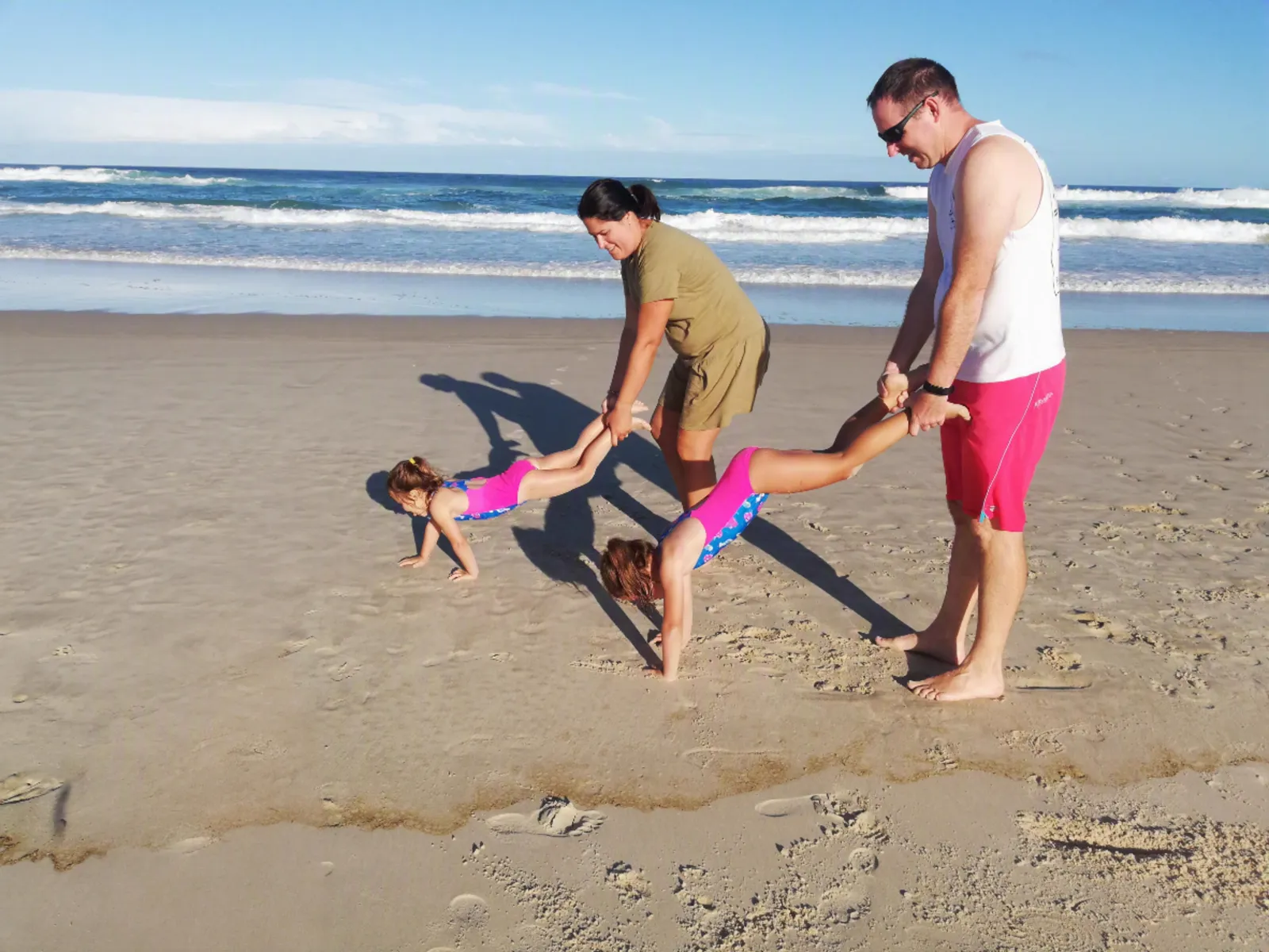 Parents and children playing wheelbarrow races on the beach