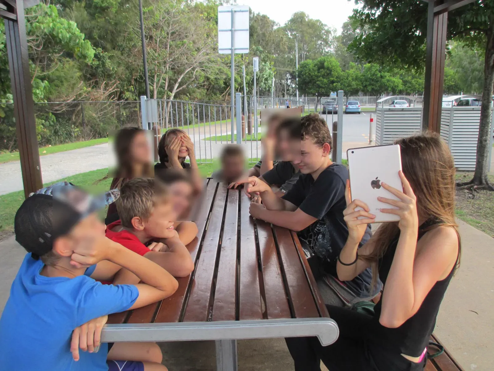 Ten children around a picnic table, mid-conversation
